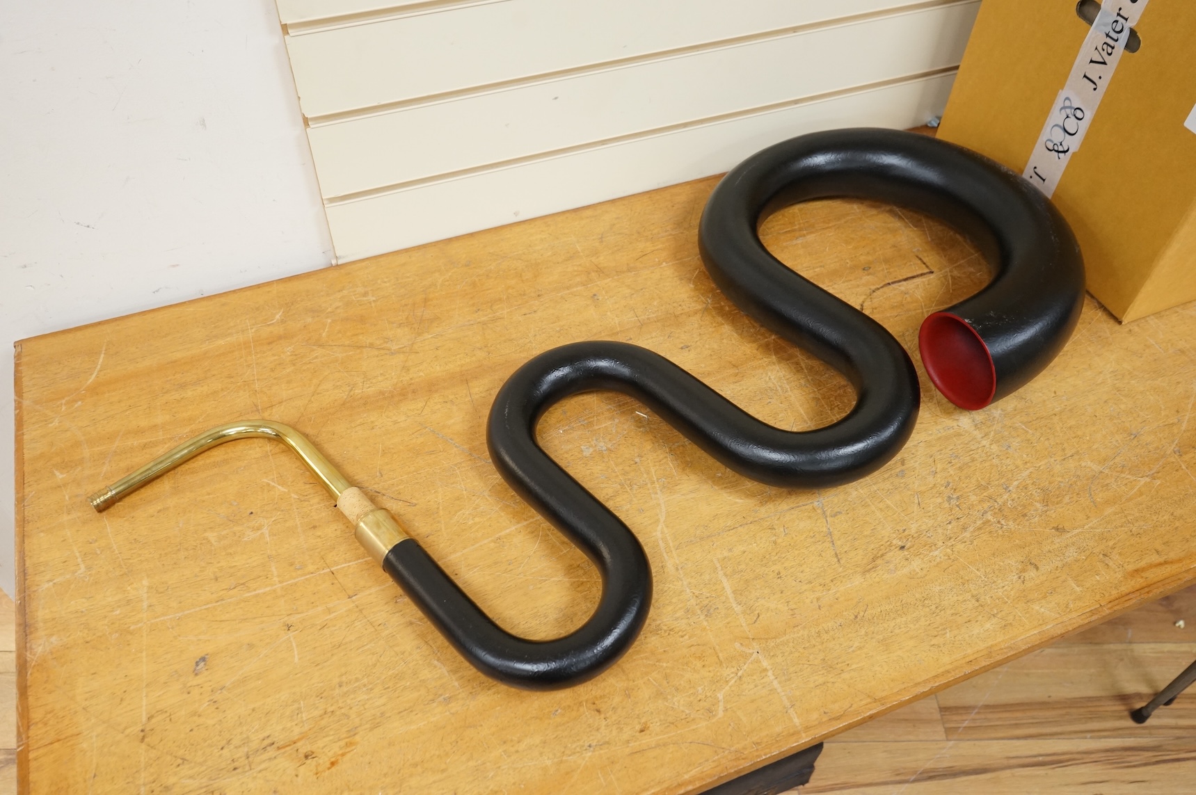 A black painted serpent open hole wind musical instrument, with brass neck (missing mouthpiece).